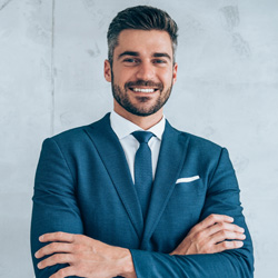 Smiling business executive in blue suit standing in an office with arms crossed