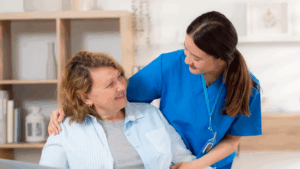 Healthcare worker in blue scrubs provides compassionate care to smiling senior patient in bright medical facility
