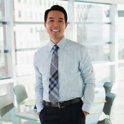 Smiling professional in shirt and tie standing in conference room with hands in pockets