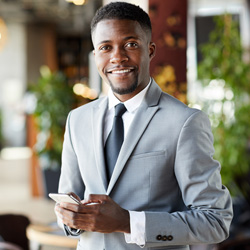 Smiling professional in business suit standing in a lobby holding a smartphone