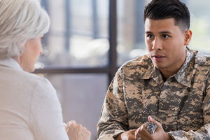 Military member wearing camo and speaking to a PMHNP during a VA visit