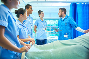 Doctor instructing students in front of a patient